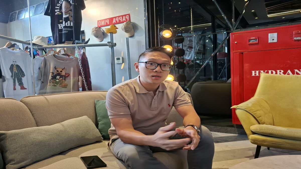 MTQ Nasional XXXI Bawa Dampak Dahsyat! Okupansi Hotel Semarang Diproyeksi Capai 90 Persen 51 Seorang pria berkacamata duduk di sofa krem di dalam ruangan, dengan latar belakang rak pakaian dan kotak hidran merah