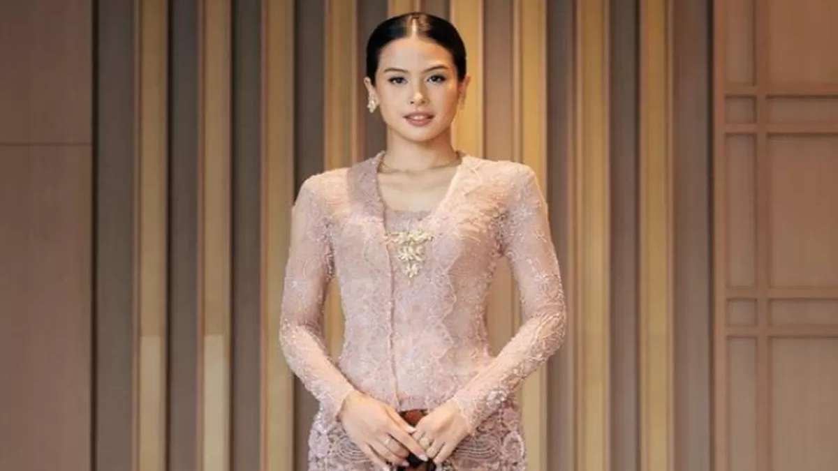 Maudy Ayunda Ajak Generasi Muda Ambil Peran Nyata sebagai Agen Perubahan Bangsa 52 Maudy Ayunda mengenakan kebaya modern berwarna merah muda lengan panjang dengan latar belakang dinding kayu bergaris