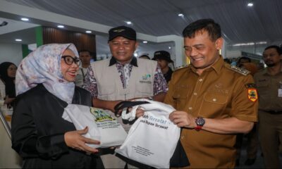 Gubernur Ahmad Luthfi menyerahkan tas belanja putih kepada seorang perempuan berkacamata dan berhijab dalam sebuah acara