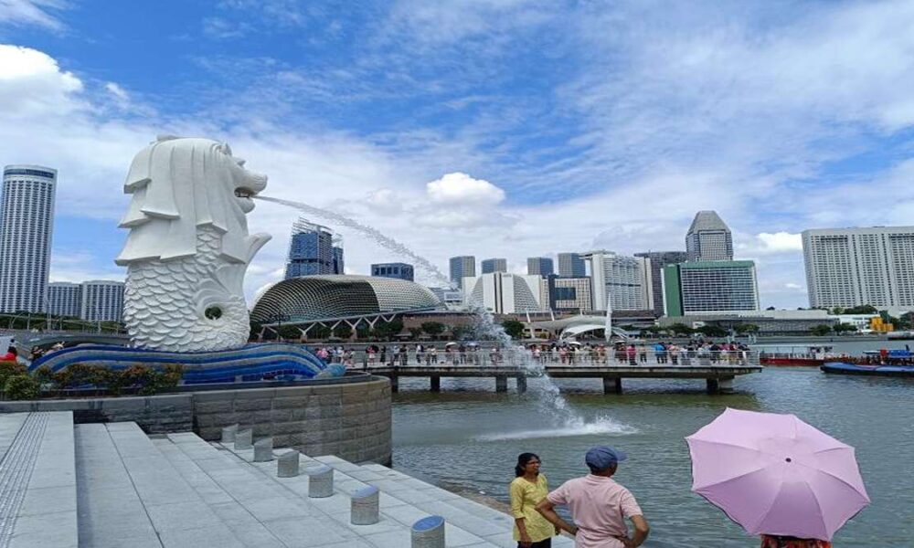 Patung Merlion menyemburkan air dengan latar belakang gedung-gedung pencakar langit di Singapura