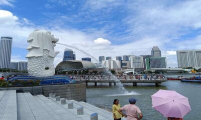 Patung Merlion menyemburkan air dengan latar belakang gedung-gedung pencakar langit di Singapura