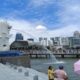 Patung Merlion menyemburkan air dengan latar belakang gedung-gedung pencakar langit di Singapura