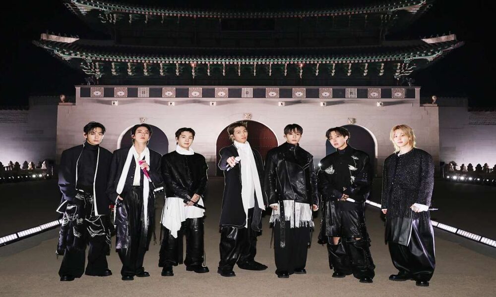 Ketujuh anggota BTS berpose bersama di depan gerbang istana bersejarah di Seoul pada malam hari