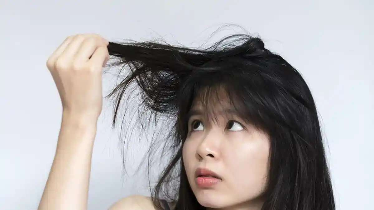 7 Rahasia Ampuh Cara Menata Rambut Agar Tidak Lepek dan Bau Setelah Olahraga 54 Seorang wanita memeriksa rambutnya yang kering dan kusut