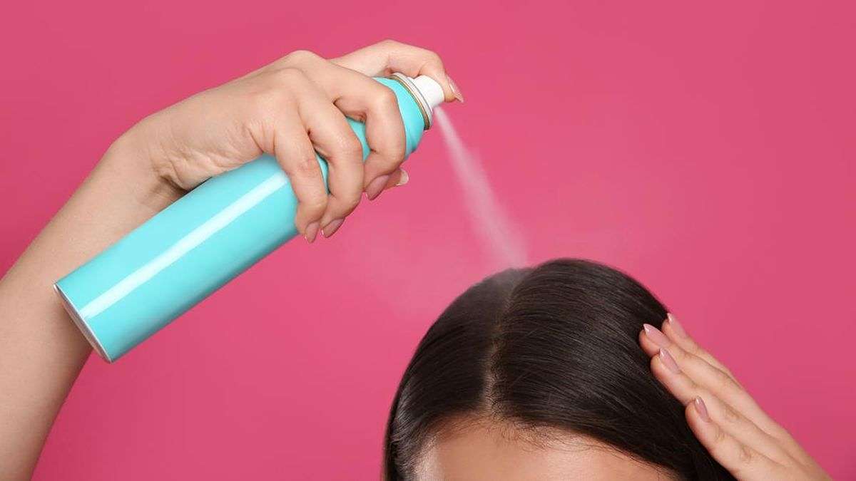 7 Rahasia Ampuh Cara Menata Rambut Agar Tidak Lepek dan Bau Setelah Olahraga 51 Seseorang menyemprotkan dry shampoo ke rambut hitam dengan latar belakang merah muda