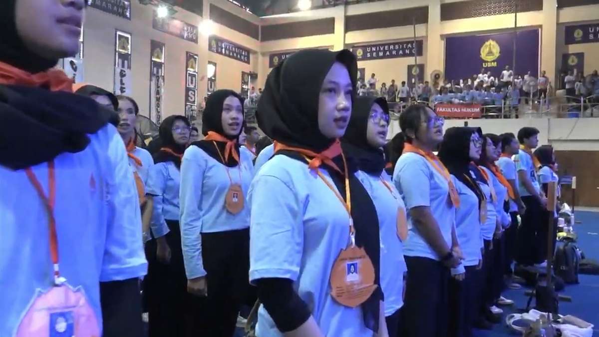Sekelompok mahasiswa berhijab mengenakan kemeja biru muda dan syal oranye dalam acara di dalam ruangan