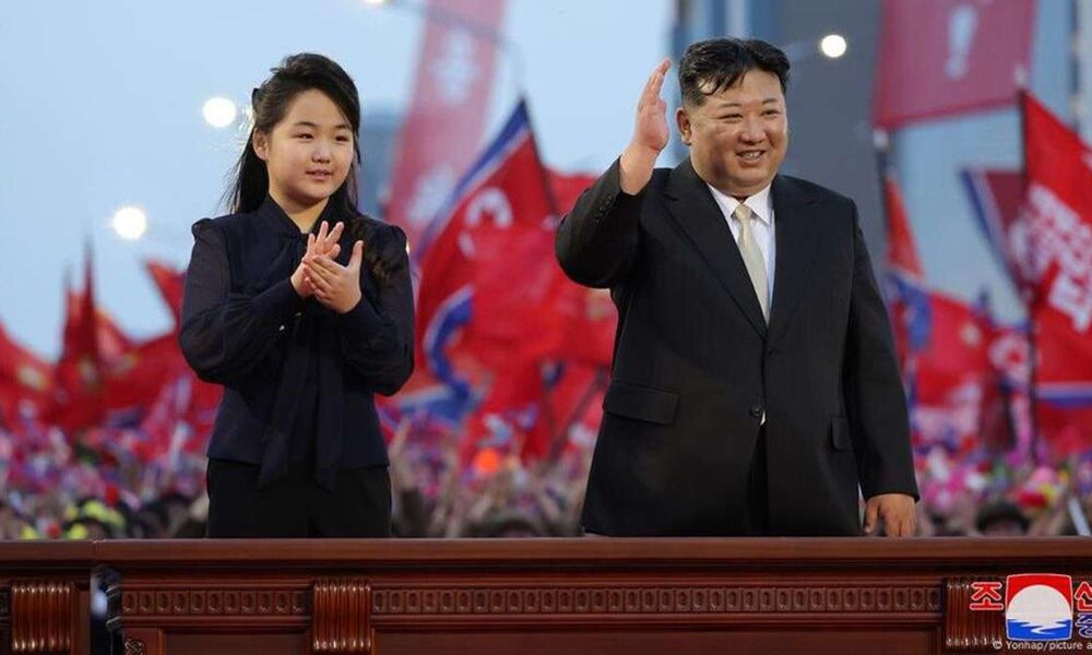 Putri Kim Jong Un, Berusia 13 Tahun Dipersiapkan Jadi Penerus, Kim Jong Un dan putrinya melambaikan tangan kepada orang banyak di depan latar belakang bendera merah di Korea Utara