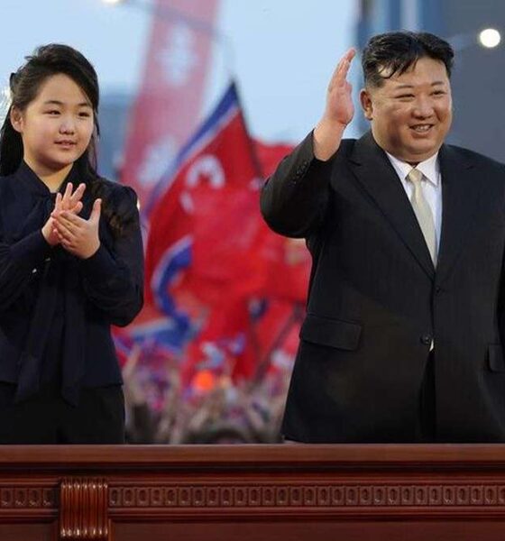 Putri Kim Jong Un, Berusia 13 Tahun Dipersiapkan Jadi Penerus, Kim Jong Un dan putrinya melambaikan tangan kepada orang banyak di depan latar belakang bendera merah di Korea Utara