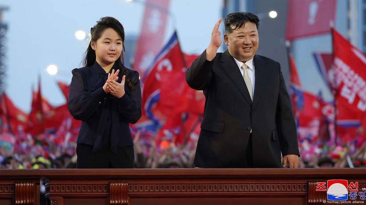 Putri Kim Jong Un, Berusia 13 Tahun Dipersiapkan Jadi Penerus, Kim Jong Un dan putrinya melambaikan tangan kepada orang banyak di depan latar belakang bendera merah di Korea Utara