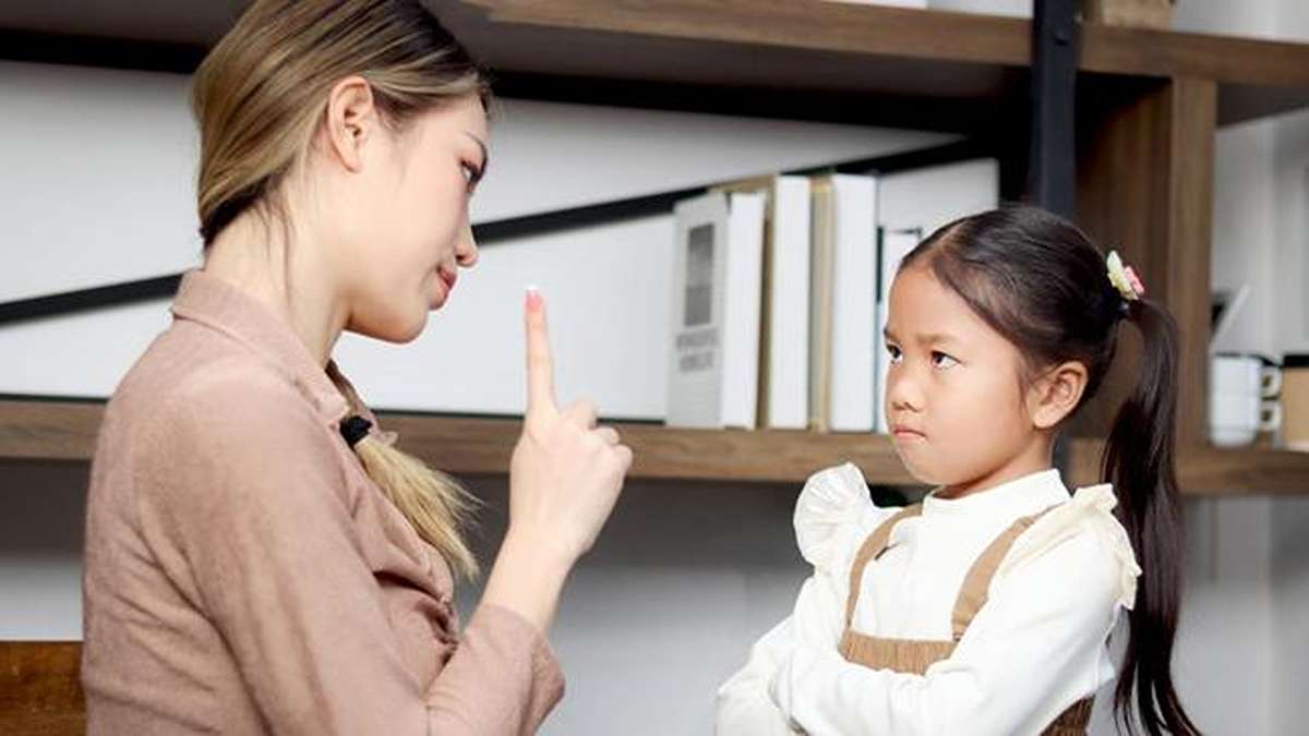 Seorang ibu yang sedang memarahi dan menasihati anak perempuannya yang bersidekap sambil cemberut