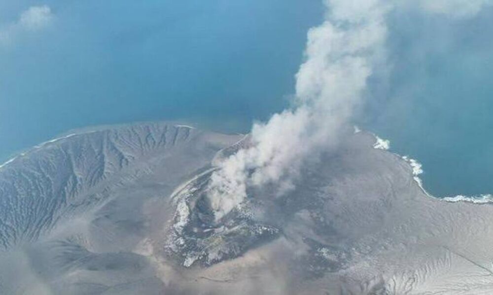 Foto udara gunung berapi yang sedang meletus dan menyemburkan debu vulkanik ke udara di atas perairan