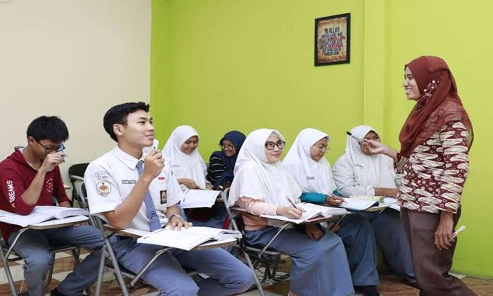 Guru wanita berhijab sedang mengajar sekumpulan siswa di dalam kelas