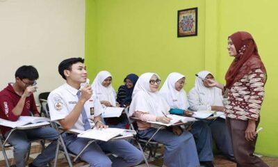 Guru wanita berhijab sedang mengajar sekumpulan siswa di dalam kelas