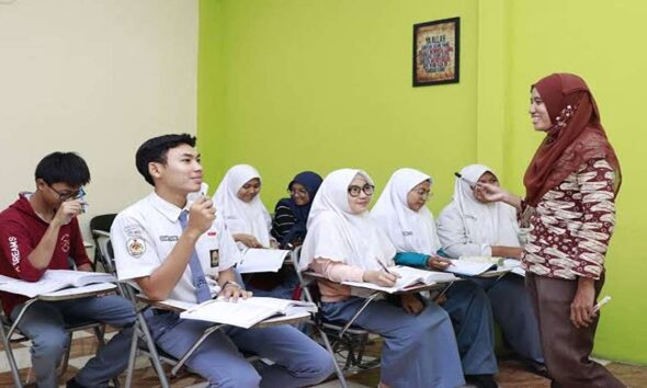Guru wanita berhijab sedang mengajar sekumpulan siswa di dalam kelas