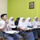 Guru wanita berhijab sedang mengajar sekumpulan siswa di dalam kelas