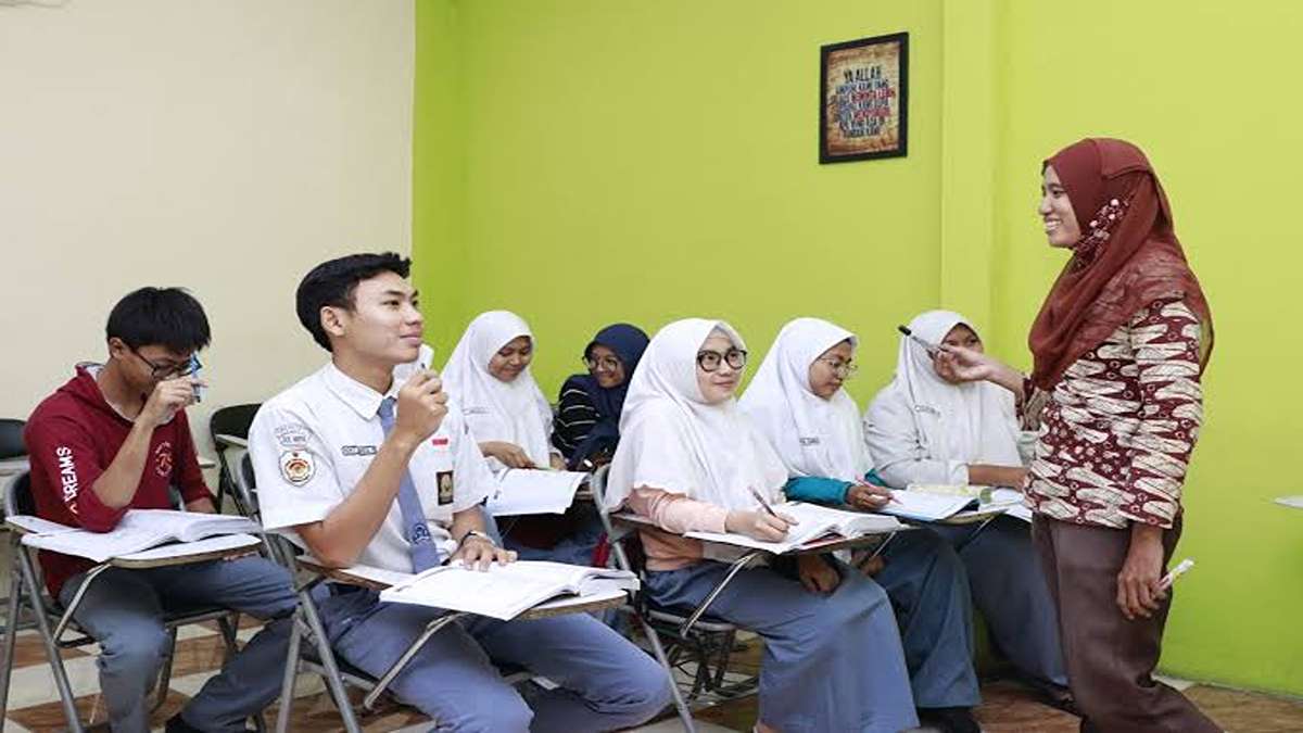 Guru wanita berhijab sedang mengajar sekumpulan siswa di dalam kelas