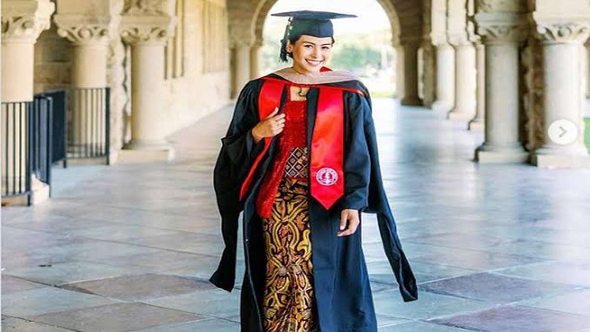 Maudy Ayunda Ajak Generasi Muda Ambil Peran Nyata sebagai Agen Perubahan Bangsa 51 Seorang mahasiswi tersenyum mengenakan toga kelulusan dan kebaya tradisional dengan bawahan kain batik