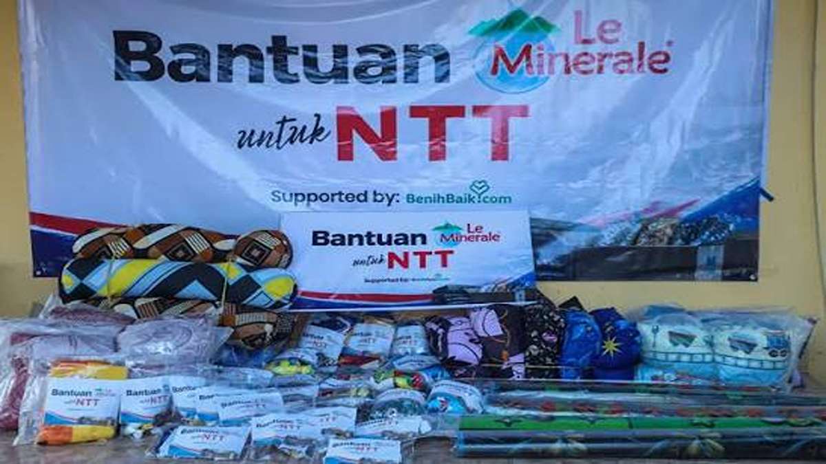 Spanduk Le Minerale Bantuan untuk NTT dengan tumpukan bantuan logistik di depannya