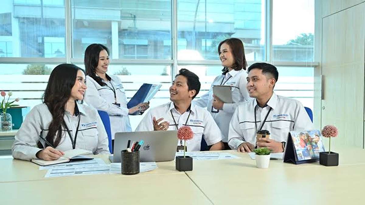 Sekelompok karyawan tersenyum ramah di ruang kerja modern