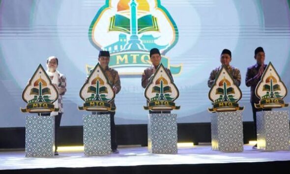 Lima orang pejabat berdiri di atas panggung di depan podium bermotif untuk meresmikan pembukaan MTQ