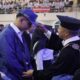 Inspiratif! Mahasiswa Baru USM Didorong Cerdas Saring Informasi di Era Digital 55 Seorang pejabat universitas mengenakan topi toga dan jubah hitam sedang memasangkan topi biru kepada seorang mahasiswa baru dalam acara pelantikan di dalam aula