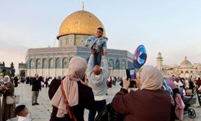Seorang pria mengangkat anak laki-lakinya di kompleks Masjid Al-Aqsa dengan Kubah Shakhrah di latar belakang