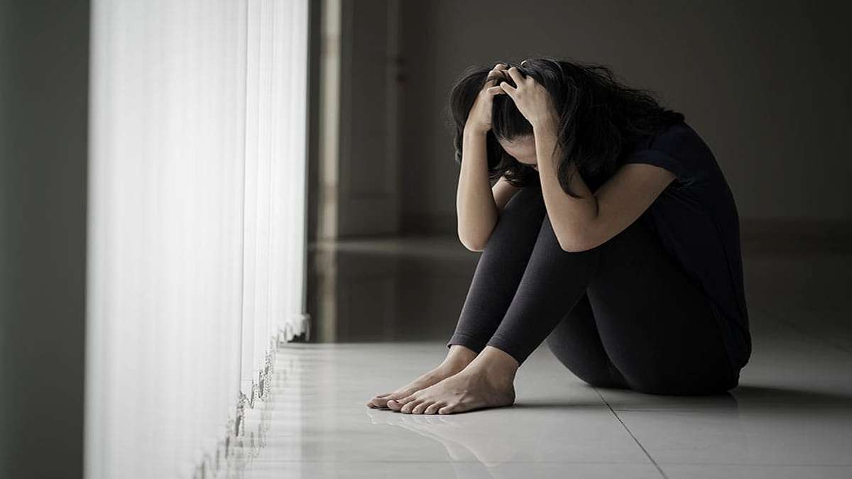 Darurat Kesehatan Mental Ribuan Warga Tangsel Terindikasi Depresi di Tengah Tekanan Modern 51 Seorang wanita duduk meringkuk di lantai dalam ruangan gelap dengan tangan memegang kepala sambil merasa tertekan
